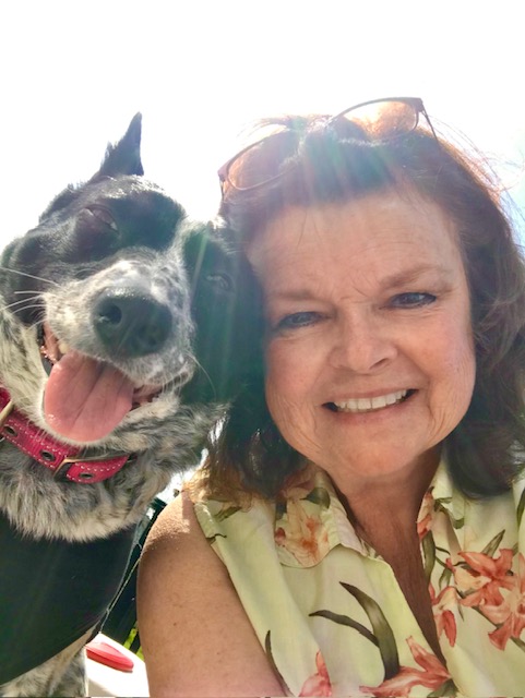 Suzanne Gonzalez, the Co-Founder and Board President, is pictured with her medium-sized black mix-breed dog, both of whom are smiling.